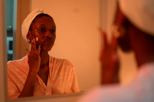 Mujer aplicándose crema en el rostro frente al espejo